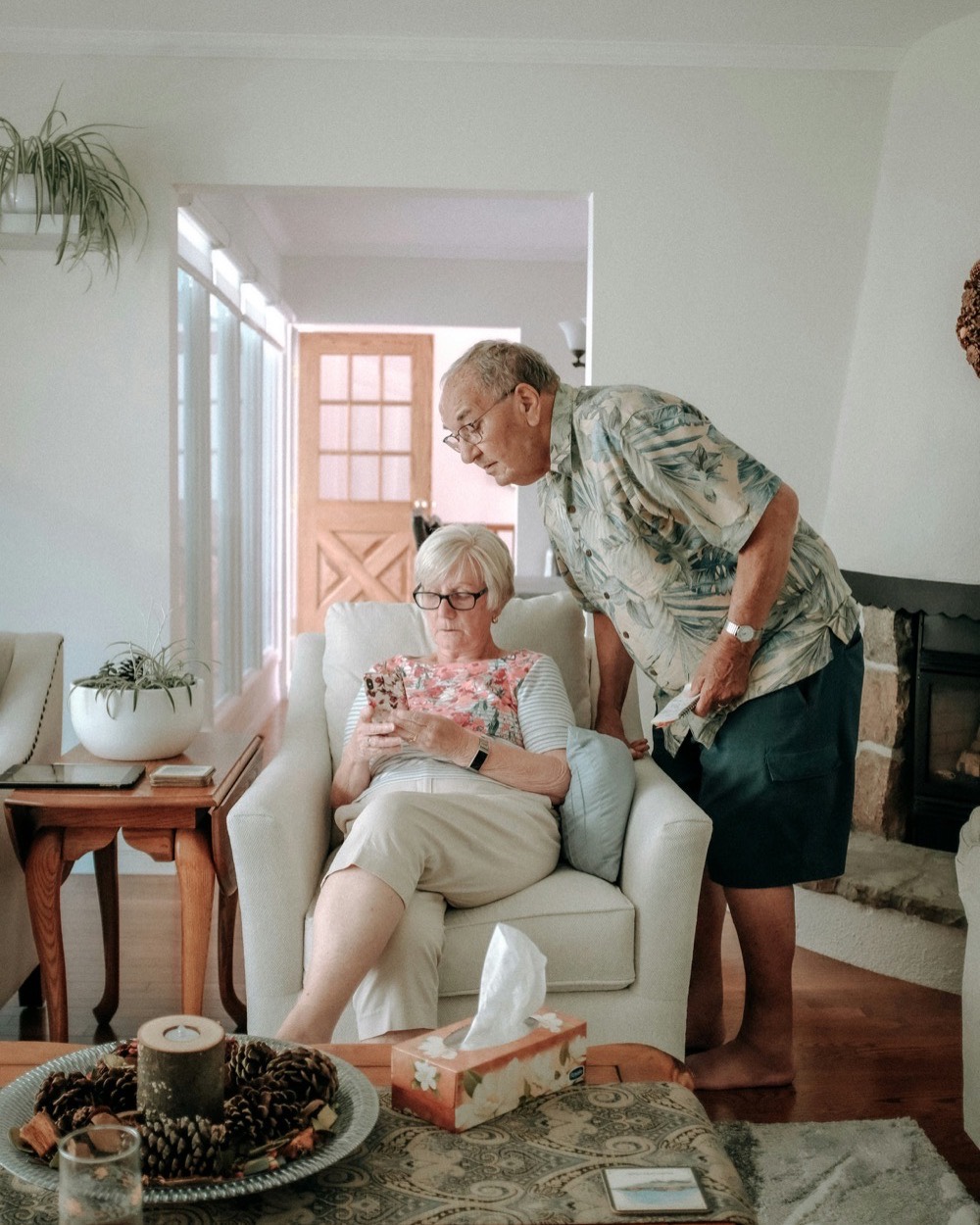 Two family members reading something together on a phone in their living room