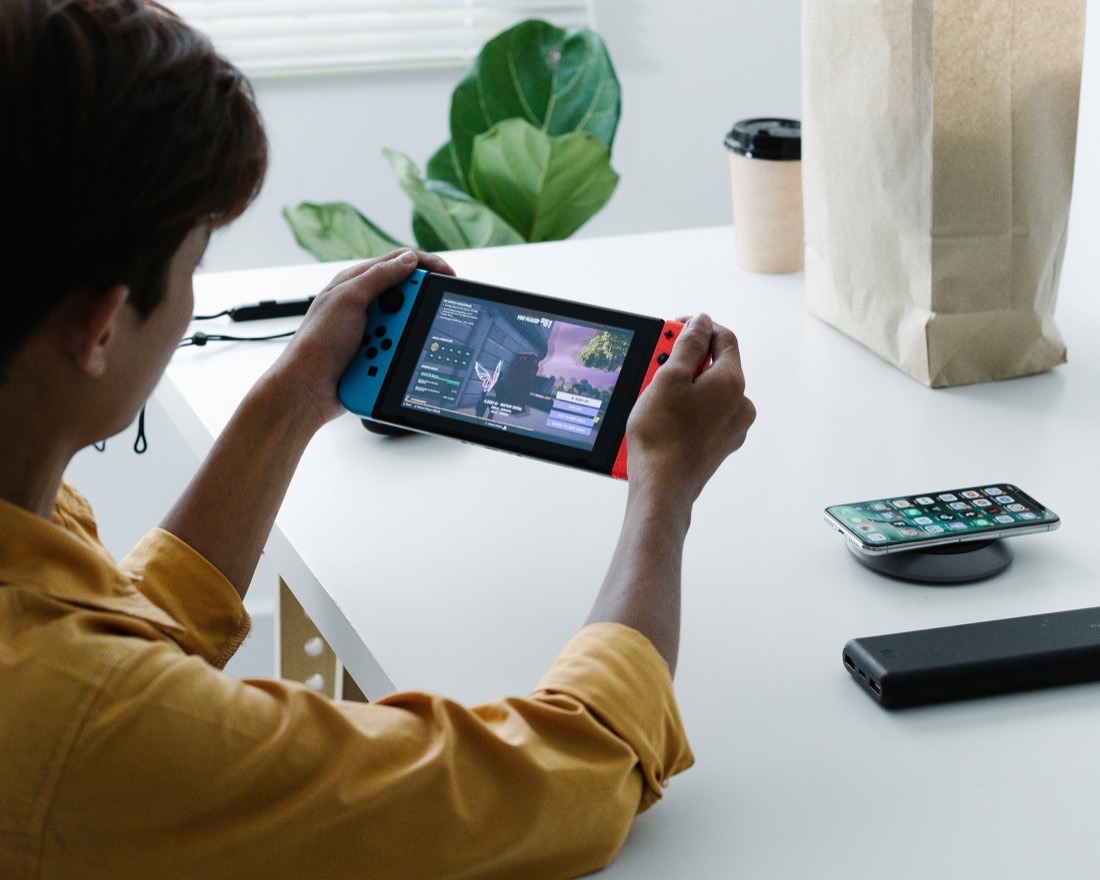 A teenager playing a handheld game console at a bright desk
